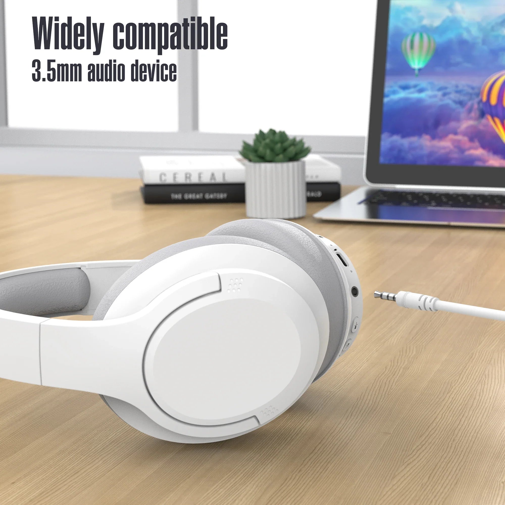 Bluetooth Wireless Over-Ear Headphones in white, featuring a 3.5mm audio jack, placed on a wooden desk with a laptop.