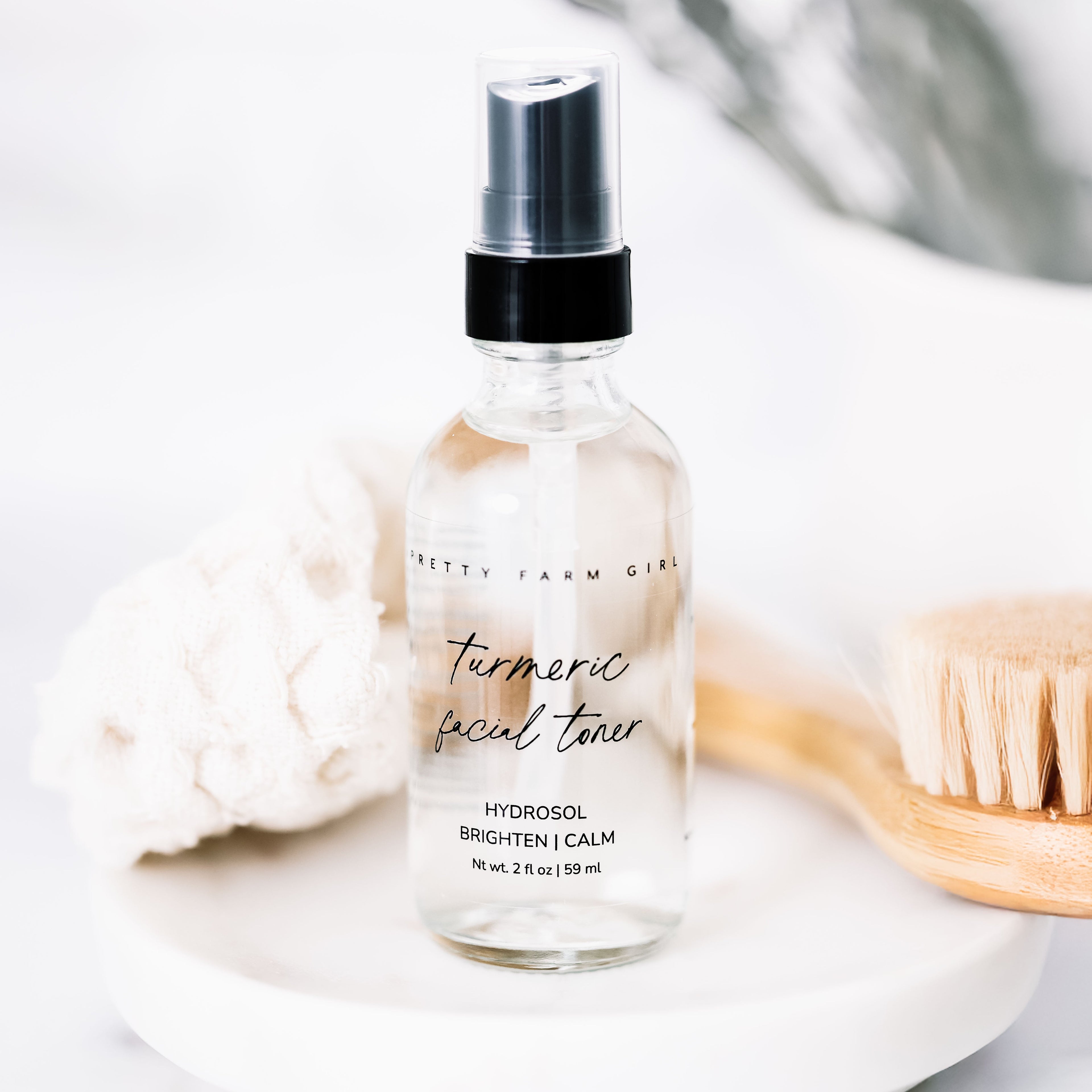 Dark Spot Brightening Kit featuring a turmeric facial toner in a clear spray bottle, with a wooden brush and soft cloth in th