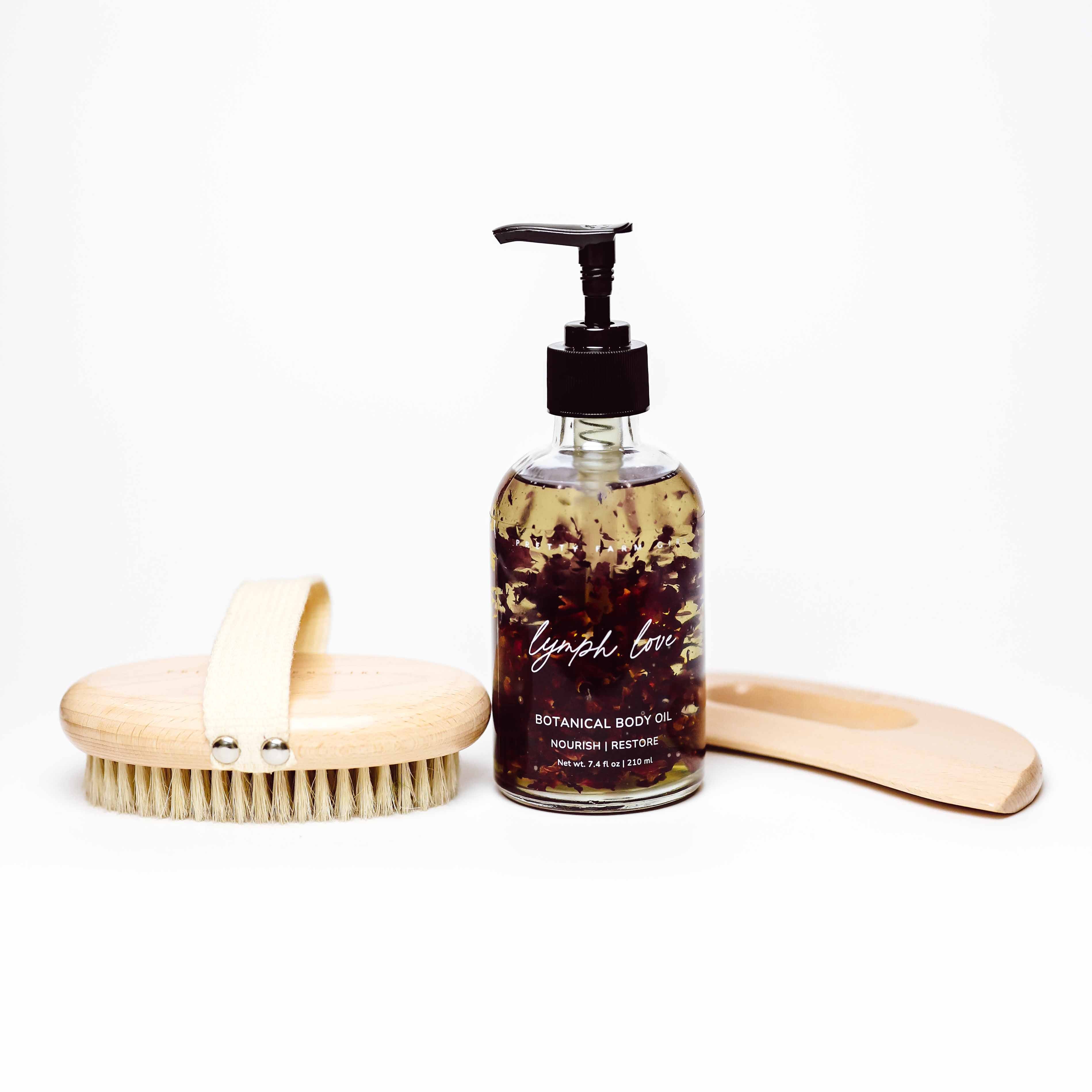 Body Care Lymphatic Routine Kit featuring a bottle of botanical body oil, a wooden dry brush, and a massage tool.