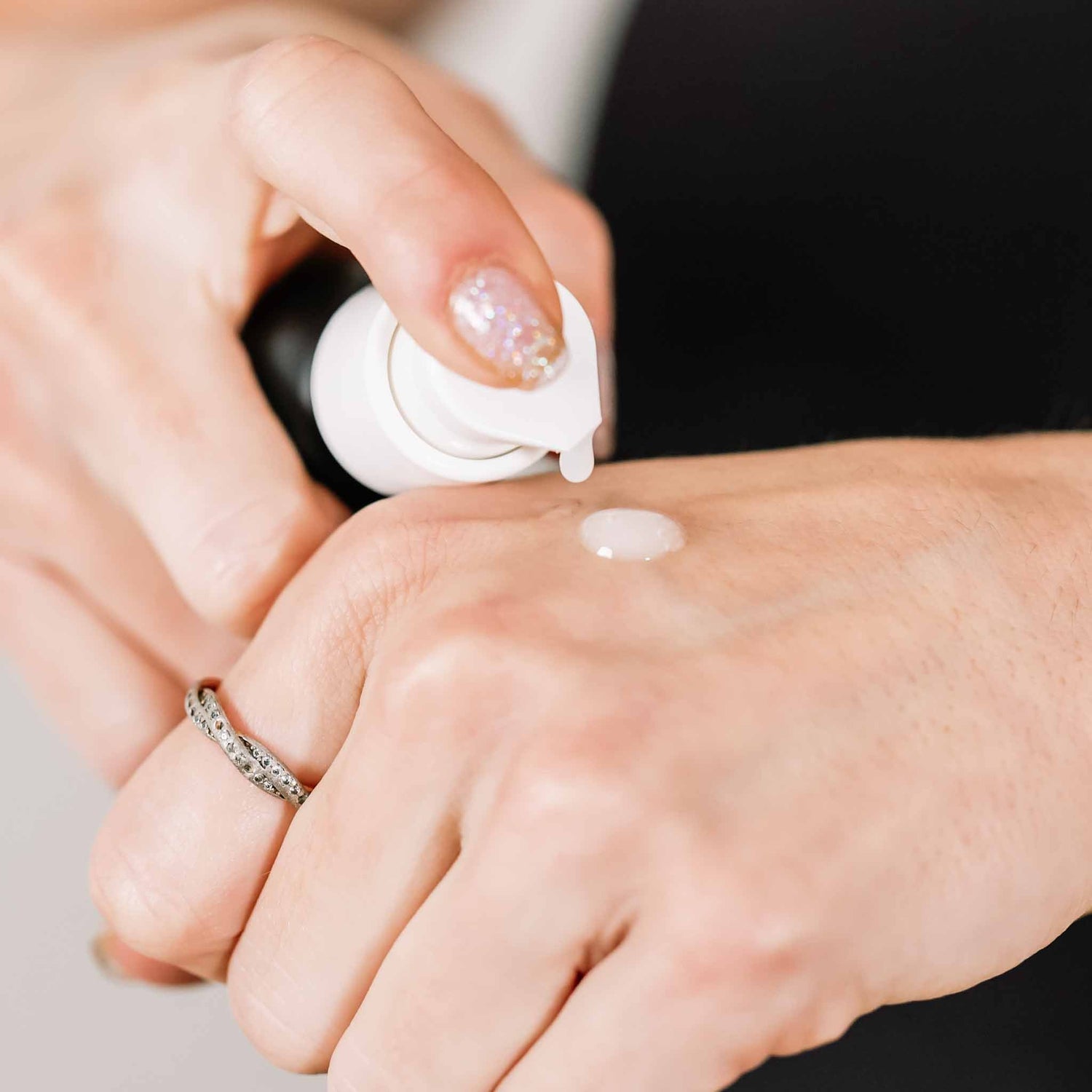Emu Oil Serum in a pump bottle, dispensing a lightweight, clear serum onto a hand with a ring. Fragrance-free for sensitive s