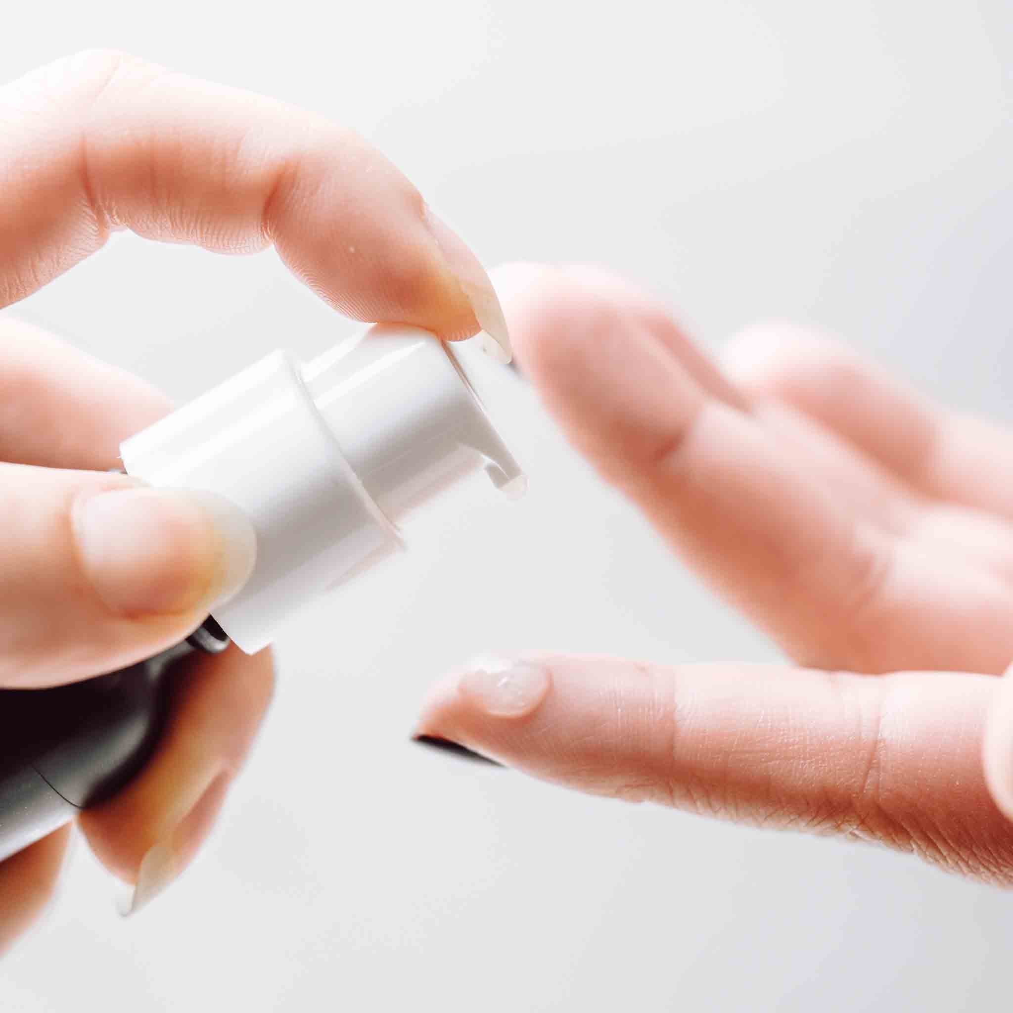 Emu Oil Serum in a pump bottle, being dispensed onto a fingertip, showcasing its lightweight, fragrance-free formula.