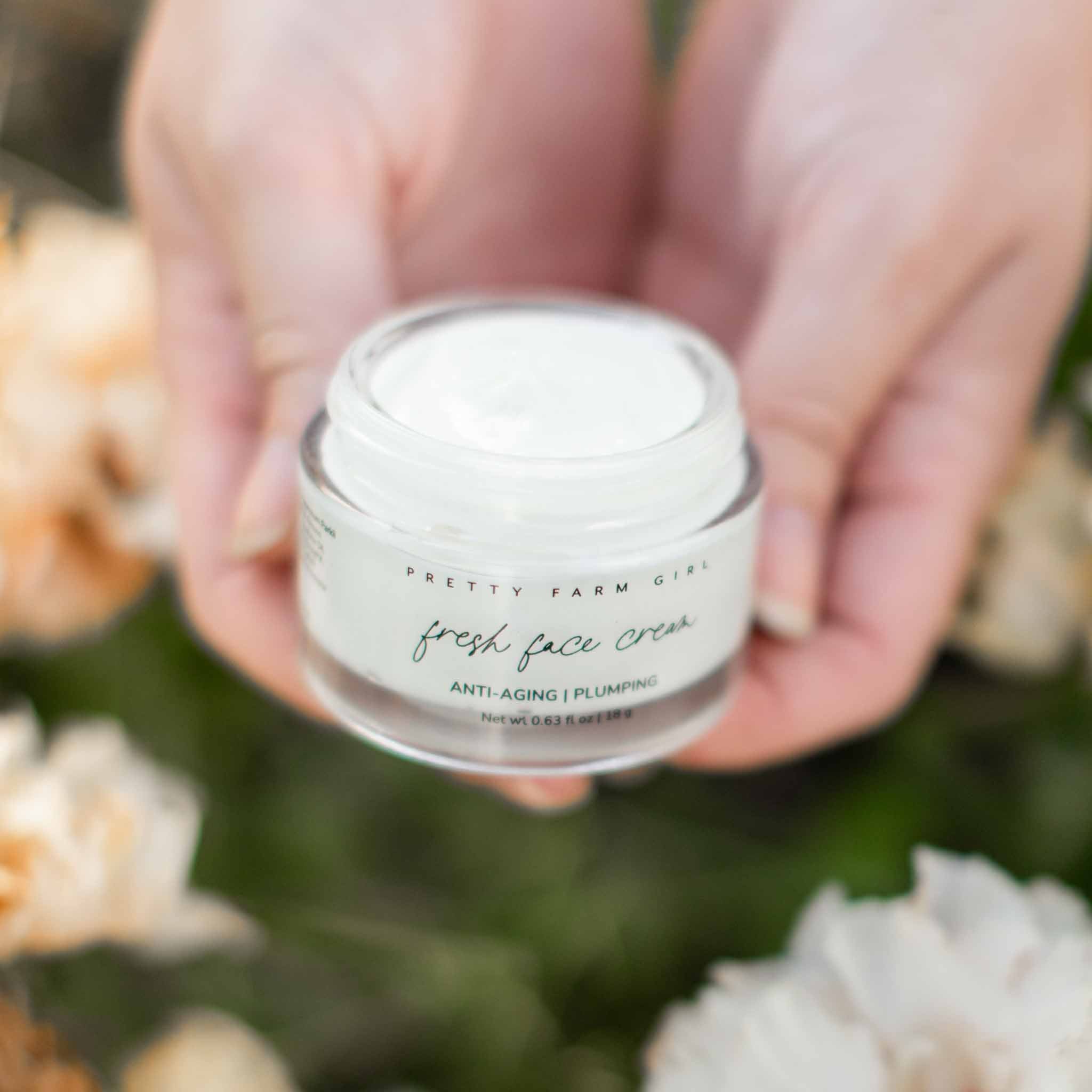 Dark Spot Brightening Kit featuring a jar of Fresh Face Cream held between hands, surrounded by soft floral background.