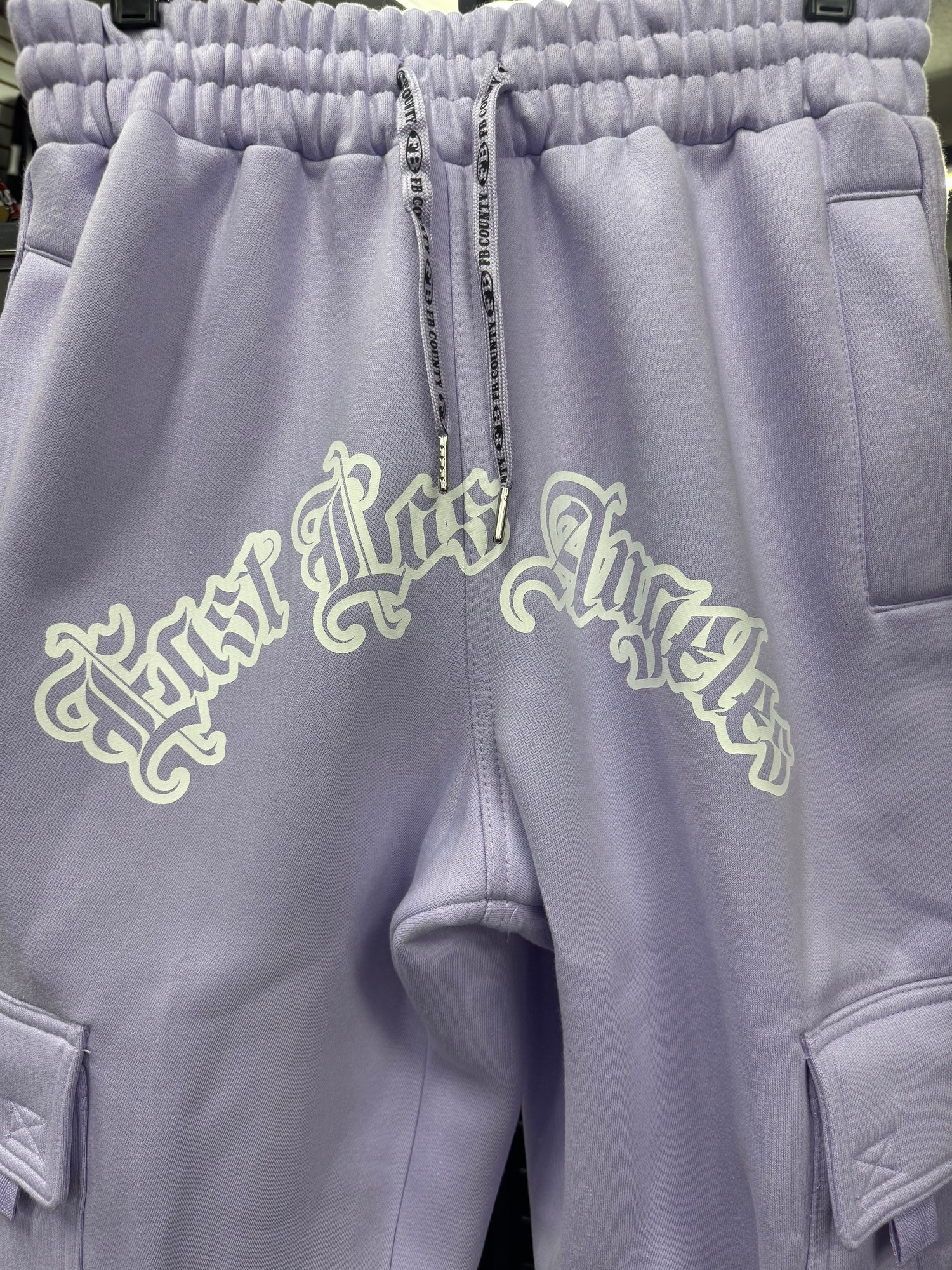 FB County Fleece Cargo Pants in lavender with "East Los Angeles" graphic in white on the front. Features cargo pockets.