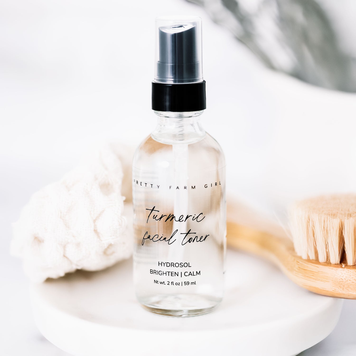 Dark Spot Brightening Kit featuring a turmeric facial toner in a clear spray bottle, with a wooden brush and soft cloth in th