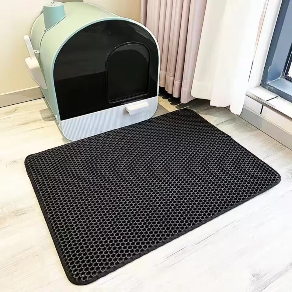 Mess-free litter mat in black, placed on a light floor next to a modern litter box. Ideal for trapping litter.